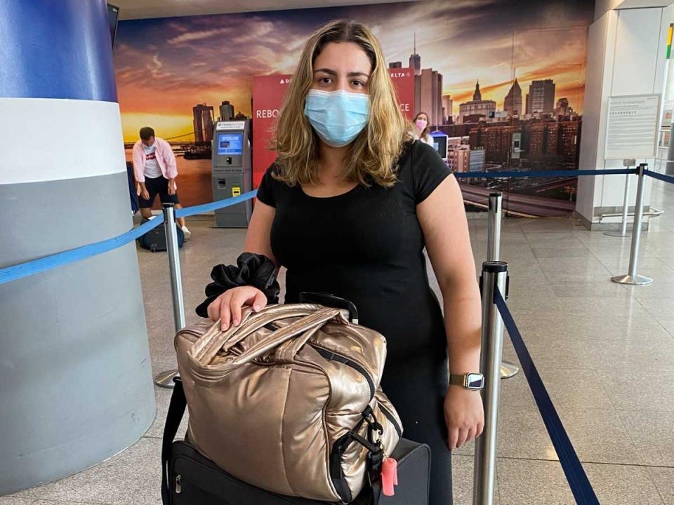 The writer with her luggage, wearing a face mask, at JFK Airport.