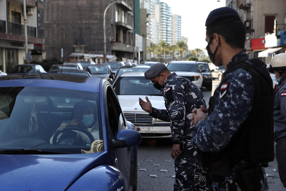 Police officers speak to a driver at a checkpoint while inspecting cars for violating a lockdown to help prevent the spread of the coronavirus, in Beirut Lebanon, Thursday, Jan. 21, 2021. Authorities on Thursday extended a nationwide lockdown by a week to Feb. 8 amid a steep rise in coronavirus deaths and infections that has overwhelmed the health care system. (AP Photo/Bilal Hussein)