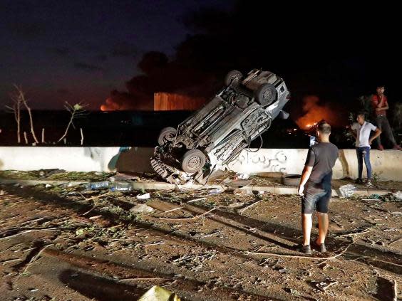 People gather by cars destroyed by the explosion (AFP via Getty Images)