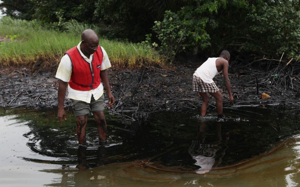 Men walk in an oil slick covering a creek near Bodo City in the oil-rich Niger Delta region of Nigeria - Sunday Alamba/AP Photo
