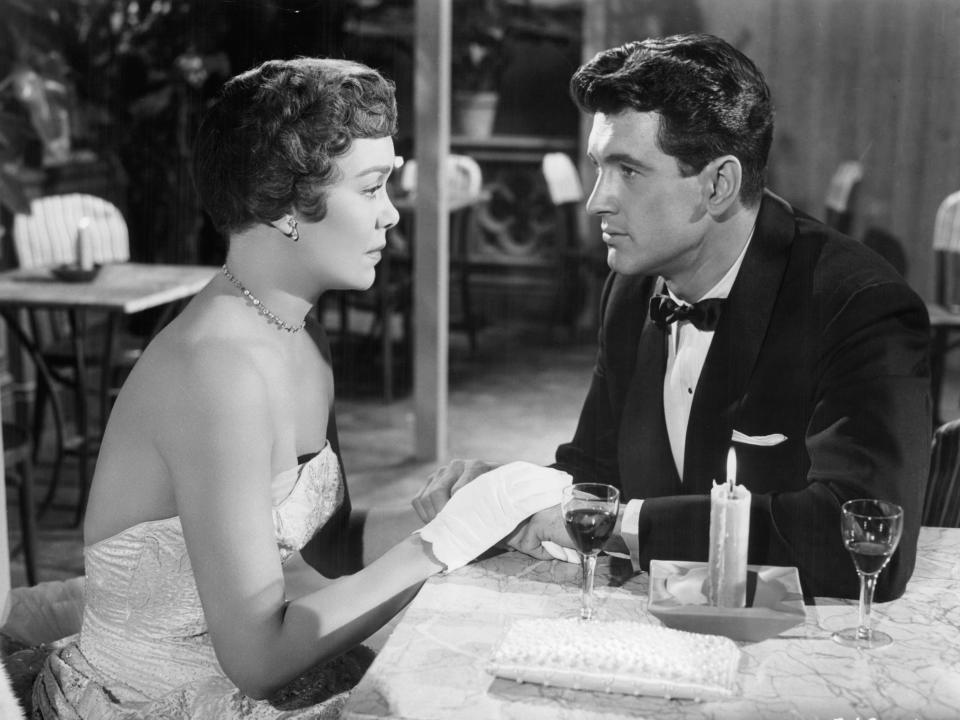 Jane Wyman and Rock Hudson holding hands at table in a scene from the film 'Magnificent Obsession', 1954.