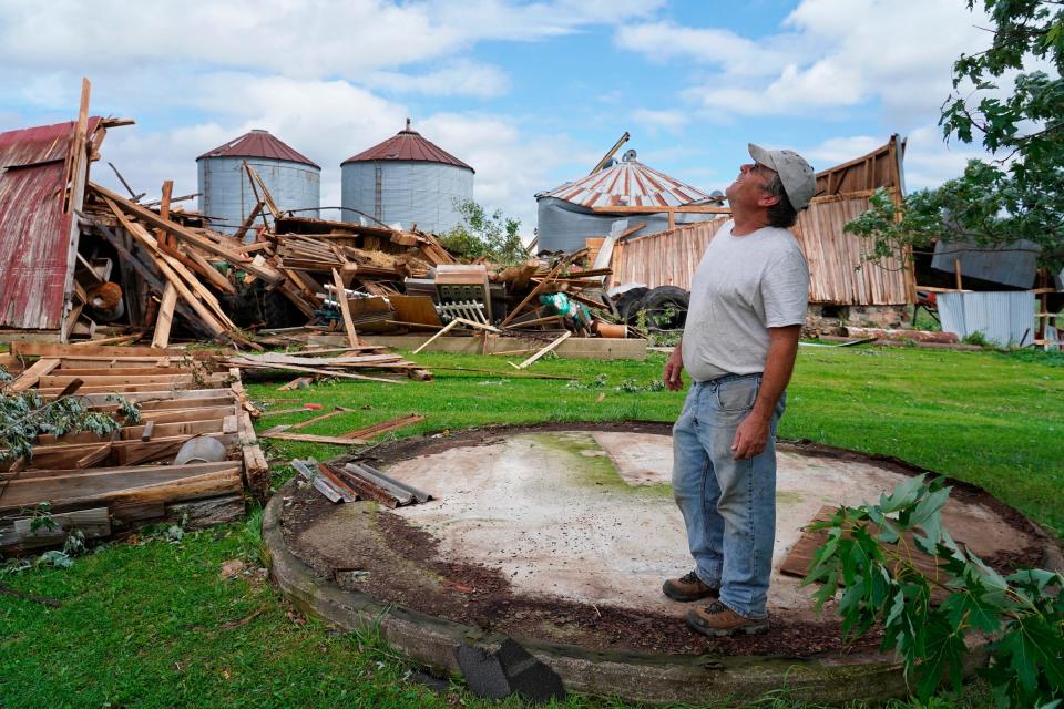 Mark Benjamin, of Williamston, looks up at a plane passing overhead while standing where a 10-foot-tall metal grain bin stood before a tornado ripped it away, sending it into a field, as well as destroying two barns and a corn bin on his property on Friday, Aug. 25, 2023. One of the hundred-year-old barns housed farm machinery and props from his Bestmaze haunted corn maze across the street that he has operated for 22 years.