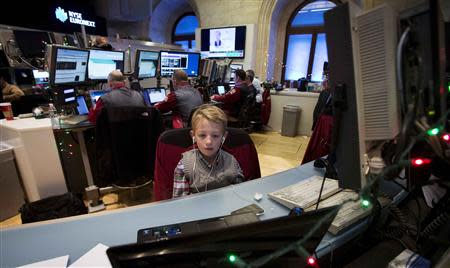 Danny Coffey, the son of a trader, sits at a desk on the floor of the New York Stock Exchange in New York, December 24, 2013. REUTERS/Carlo Allegri