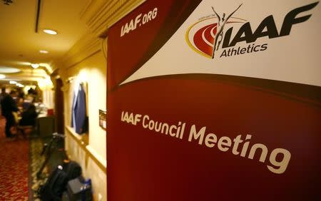 Journalists are seen near a logo of the International Association of Athletics Federations (IAAF) at a hotel where the IAAF council holds a meeting in Vienna, Austria, June 17, 2016. REUTERS/Leonhard Foeger