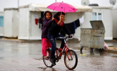 FILE PHOTO: Syrian refugee children ride a bicycle in Elbeyli refugee camp near the Turkish-Syrian border in Kilis province, Turkey, December 1, 2016. REUTERS/Umit Bektas/File Photo