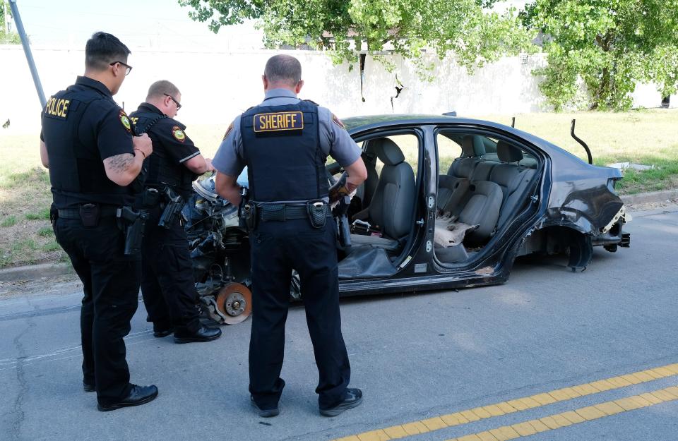 A Tulsa County Sheriff's Department deputy inspects an abandoned car found on the west side of Tulsa by Muscogee Nation Lighthorse Police Officers Daryl Wilson, left, and Kyle Johnson. They ultimately called for a wrecker to tow the car off the street.