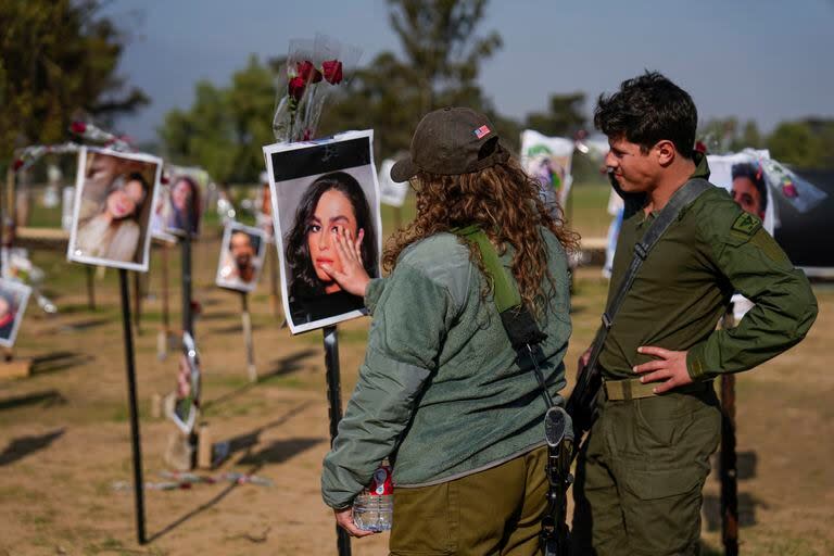 Soldados israelíes miran fotos de personas muertas o en cautiverio de Hamás durante el ataque de los milicianos al festival musical Nova en el sur de Israel, exhibidas en el lugar del hecho para conmemorar la masacre del 7 de octubre, cerca del kibbutz Re'im, viernes 1 de diciembre de 2023