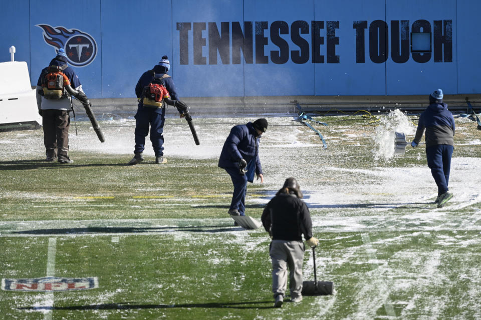 Crews remove tarps that covered the field overnight before an NFL football game between the Tennessee Titans and the Houston Texans, Saturday, Dec. 24, 2022, in Nashville, Tenn. Extreme cold weather has hit the region. (AP Photo/John Amis)