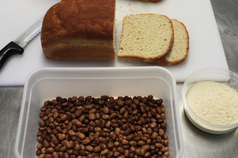 Loaf sliced next to tub of beans and a pot of flour.