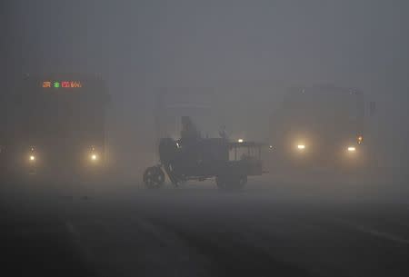 A tricycle travels past a crossroad on a hazy day in Hefei, Anhui province March 30, 2014. REUTERS/Stringer
