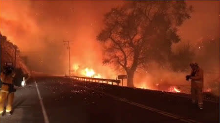 A man takes pictures of wildfires from a highway in Ojai, California, U.S. December 7, 2017 in this picture obtained from social media. INSTAGRAM @EPN106 via REUTERS