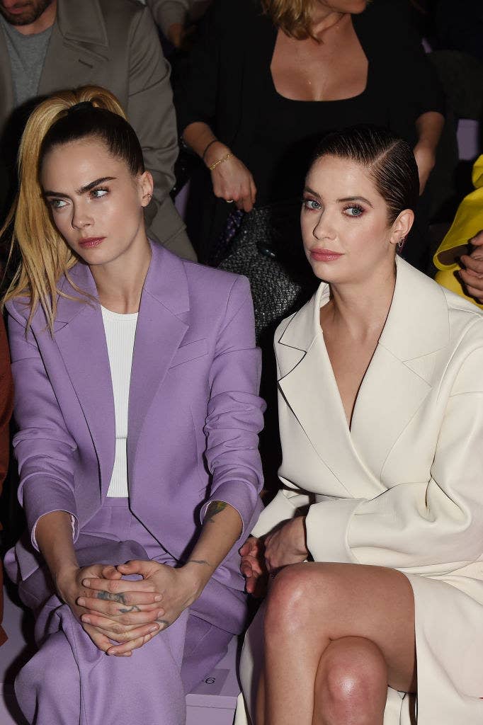 sitting together at a fashion show, the couple looks bored in their matching suits