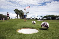 Patrick Wooten (C) holds the flag as his son Thomas, 11, misses his putt on the second half of the FootGolf course at Largo Golf Course in Largo, Florida April 11, 2015. REUTERS/Scott Audette