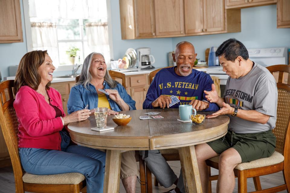 Active veterans playing cards at a table and laughing.