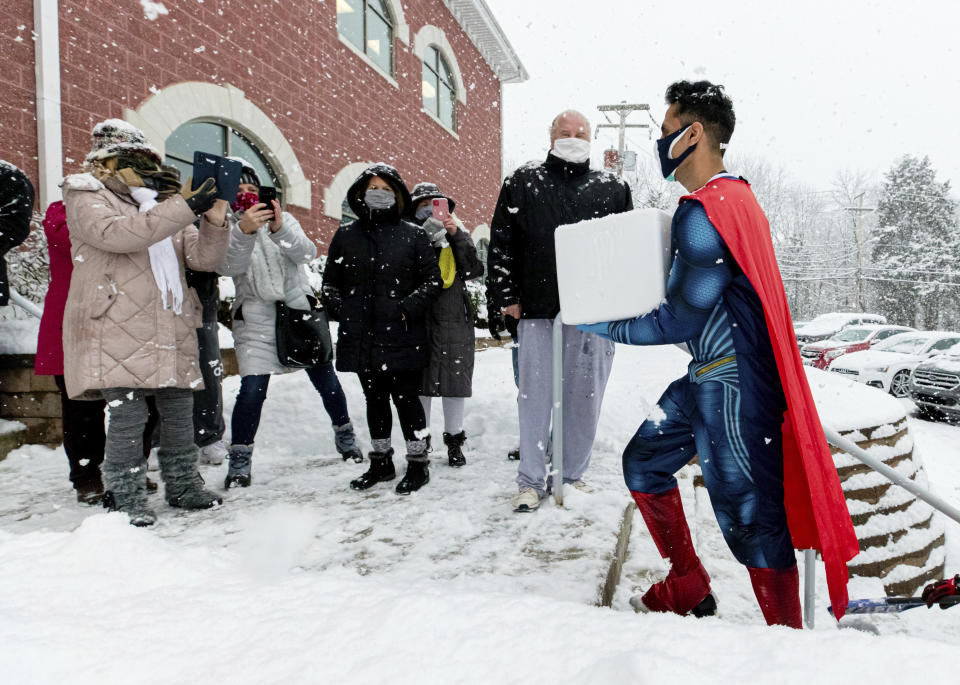 This photo provided by Chorus Media Group, Skippack Pharmacy owner & Pharmacist Dr. Mayank Amin, dressed in his trademark superhero costume, arrives in the middle of a snowstorm with vials of COVID-19 vaccine for their first vaccination clinic on Feb. 7, 2021, in Skippack, Pa. In communities across the country, local pharmacy owners are among the people administering COVID-19 vaccinations. Being a vaccine provider requires a big investment of time and paperwork, and for some, finding a location for a mass vaccination clinic. (Chorus Media Group via AP)