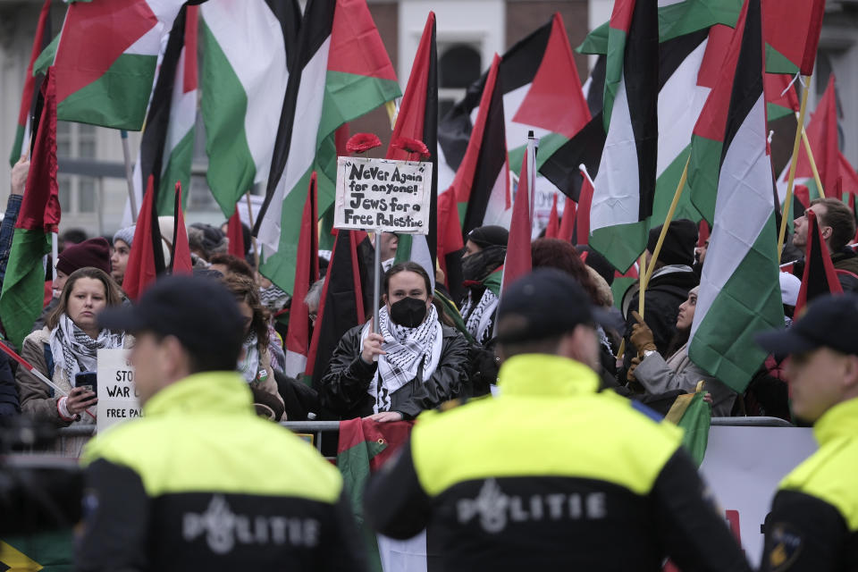 Protesters carry flags and banners outside the International Court of Justice in The Hague, Netherlands, Friday, Jan. 12, 2024. The United Nations' top court opened hearings Thursday into South Africa's allegation that Israel's war with Hamas amounts to genocide against Palestinians, a claim that Israel strongly denies. (AP Photo/Patrick Post)