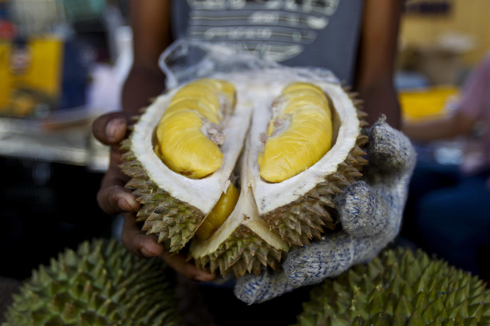 A durian vendor displays the 'Musang King' durian during the International Durian Cultural Tourism Festival in Bentong, Malaysia, Saturday, Nov. 25, 2017. (AP Photo/Sadiq Asyraf)