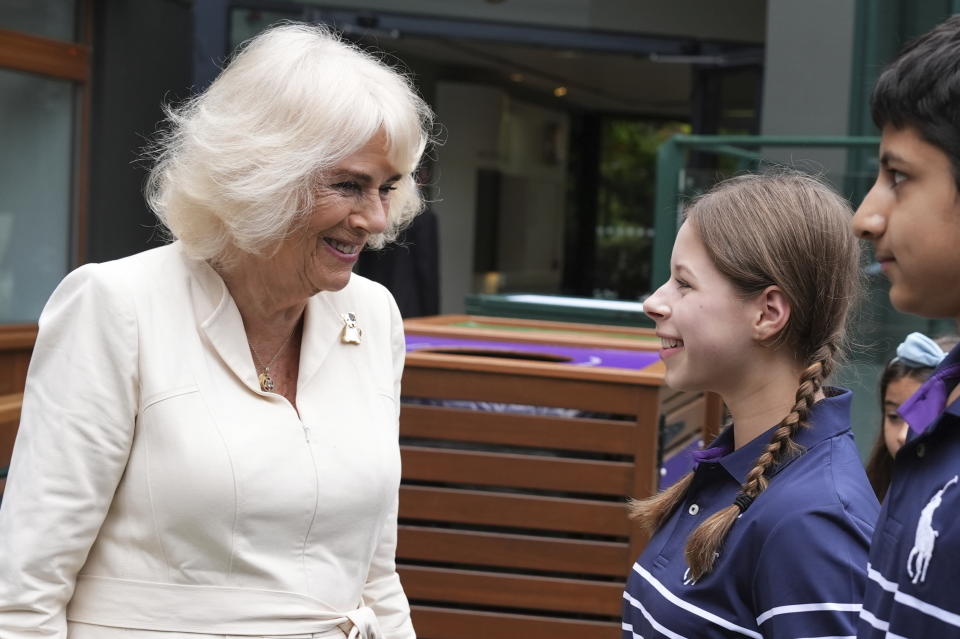 Queen Camilla meets ball kids Natalia from Burntwood School in Wandsworth and Yug from Harris Academy Wimbledon during a visit to the All England Lawn Tennis and Croquet Club in Wimbledon, south west London, on day ten of the 2024 Wimbledon Championships, Wednesday July 10, 2024. (Jordan Pettitt/Pool photo via AP)