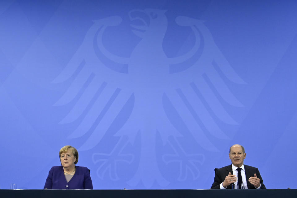 German Chancellor Angela Merkel, left, and Finance Minister Olaf Scholz speak during a press conference following a meeting with the heads of government of Germany's federal states at the Chancellery in Berlin, Thursday, Dec. 2, 2021. Merkel said Thursday that people who aren't vaccinated will be excluded from nonessential stores, cultural and recreational venues, and parliament will consider a general vaccine mandate, as part of an effort to curb coronavirus infections that again topped 70,000 newly confirmed cases in a 24-hour period. (John Macdougall/Pool Photo via AP)