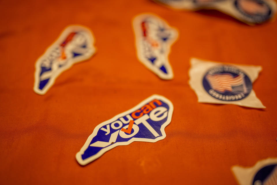 Stickers sit on a table where Brandon Rivers works to sign up voters a The Roof Above, Friday, Aug. 4, 2023, in Charlotte, N.C. A North Carolina photo voter identification law enacted nearly five years ago but got stuck in litigation is finally being implemented with this fall's municipal elections that wrap up next week. (AP Photo/Chris Carlson)