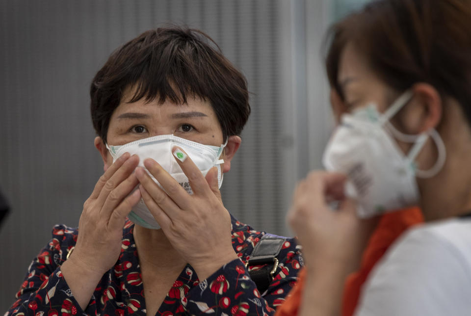 Tourists from Wuhan, China, some with double-layered face masks, stand in a line for a charter flight back to Wuhan at the Suvarnabhumi airport, Bangkok, Thailand, Friday, Jan. 31, 2020. A group of Chinese tourists who have been trapped in Thailand since Wuhan was locked down due to an outbreak of new virus returned to China on Friday. (AP Photo/Gemunu Amarasinghe)