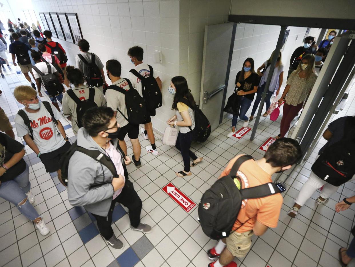 Students at Corinth High School follow the directional signage posted on the floor and keep foot traffic moving in the proper direction as they change classes on the first day back to school Monday 27 July 2020: (2020 The Associated Press)