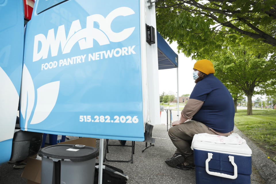 Des Moines Area Religious Council Food Pantry worker Patrick Minor sits on a cooler full of ground pork packages during a pantry stop, Wednesday, May 20, 2020, in Des Moines, Iowa. As food banks have struggled to meet soaring demand from people suddenly out of work because of the coronavirus outbreak, it has been especially troubling to see farmers have to bury produce, dump milk and euthanize hogs. Now some states are spending more money to help pay for food that might otherwise go to waste, the U.S. Agriculture Department is spending $3 billion to help get farm products to food banks, and a senator is seeking $8 billion more to buy farm produce for food banks. (AP Photo/Charlie Neibergall)