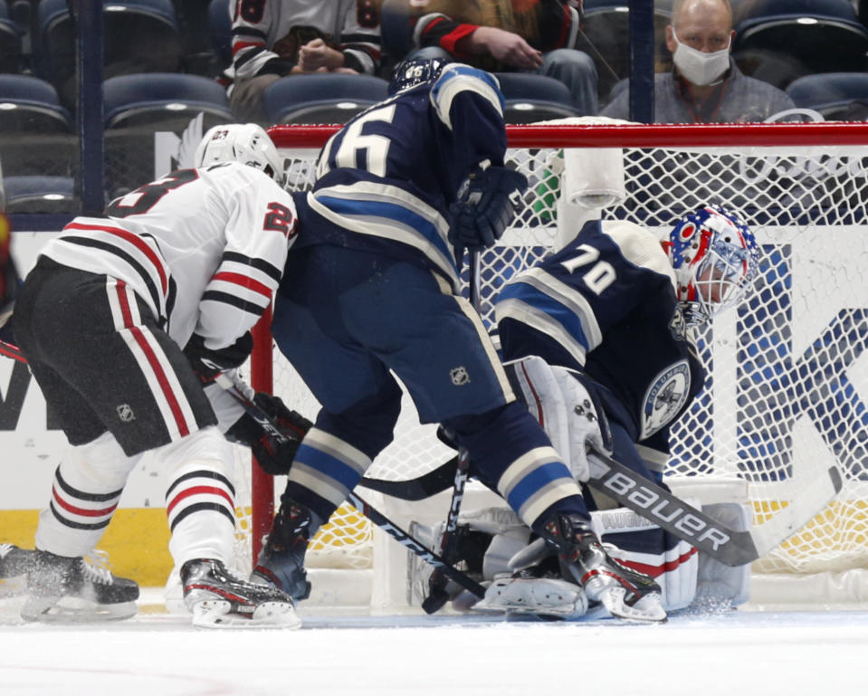 Columbus Blue Jackets goalie Joonas Korpisalo, right, stops a shot in front of teammate defenseman Dean Kukan, center, and Chicago Blackhawks forward Philipp Kurashev during the second period of an NHL hockey game in Columbus, Ohio, Monday, April 12, 2021. (AP Photo/Paul Vernon)