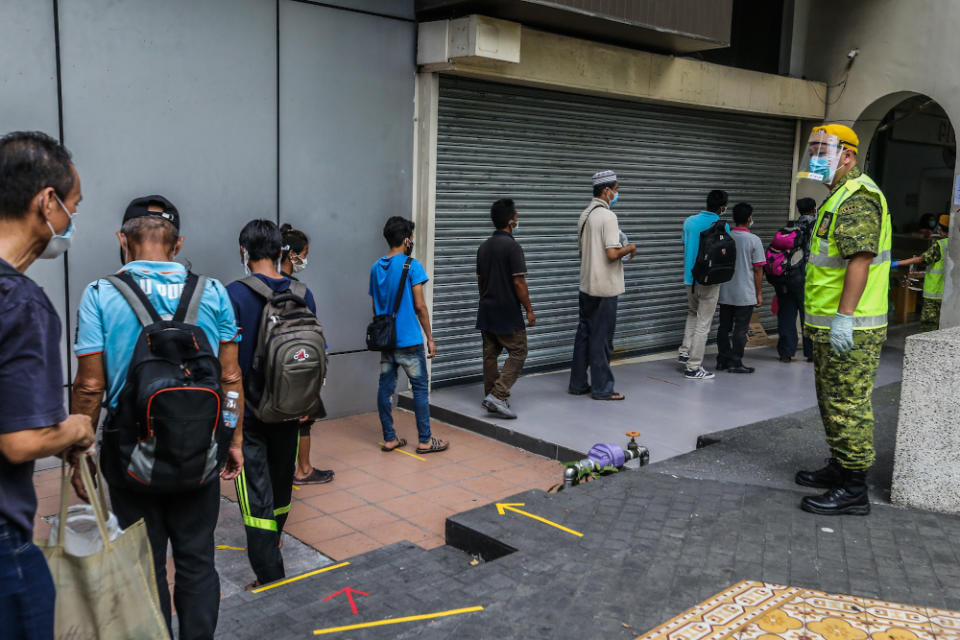 The homeless adhere to social distancing guidelines while queuing to collect food at the Pit Stop Community Cafe in Kuala Lumpur 30, 2020. — Picture by Firdaus Latif