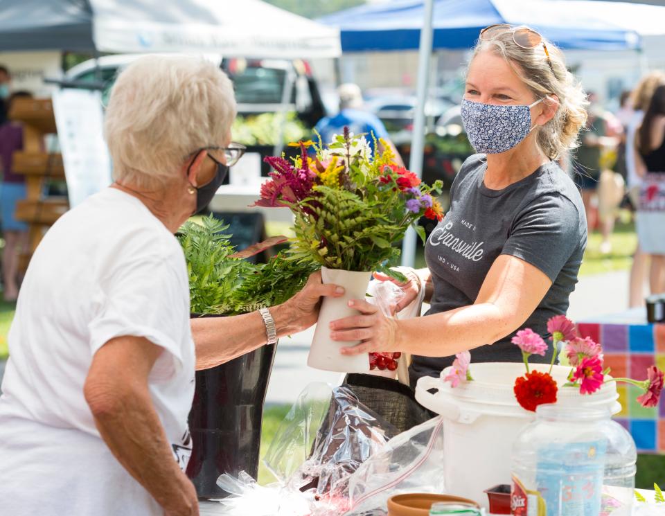 Barb Lynn, right, purchases her weekly flowers from Mary Ellen Damm of Timberview Flower Farm at the Franklin Street Bazaar Saturday afternoon, Aug. 22, 2020. Next Saturday, Aug. 29, Franklin Street will host their final bazaar.