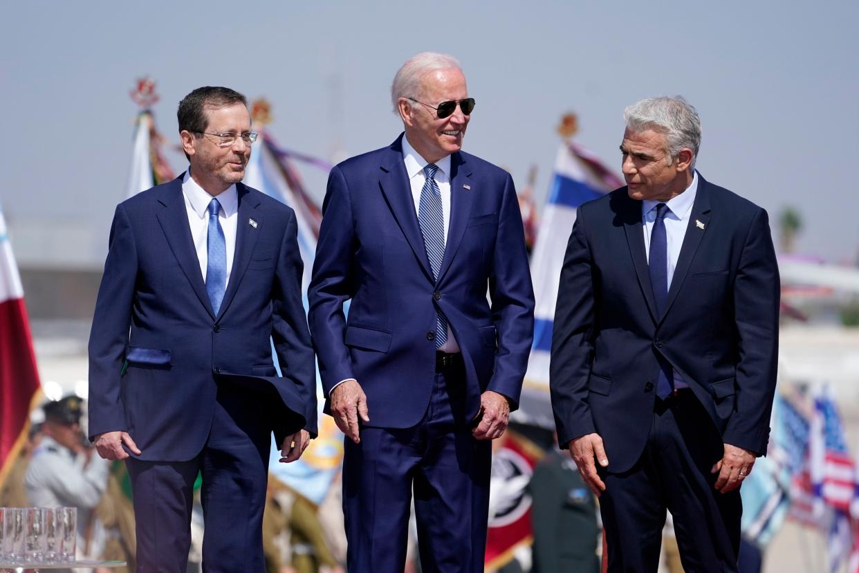 President Joe Biden stands with Israeli Prime Minister Yair Lapid, right, and President Isaac Herzog, left, lafter arriving at Ben Gurion Airport, Wednesday, July 13, 2022, in Tel Aviv.