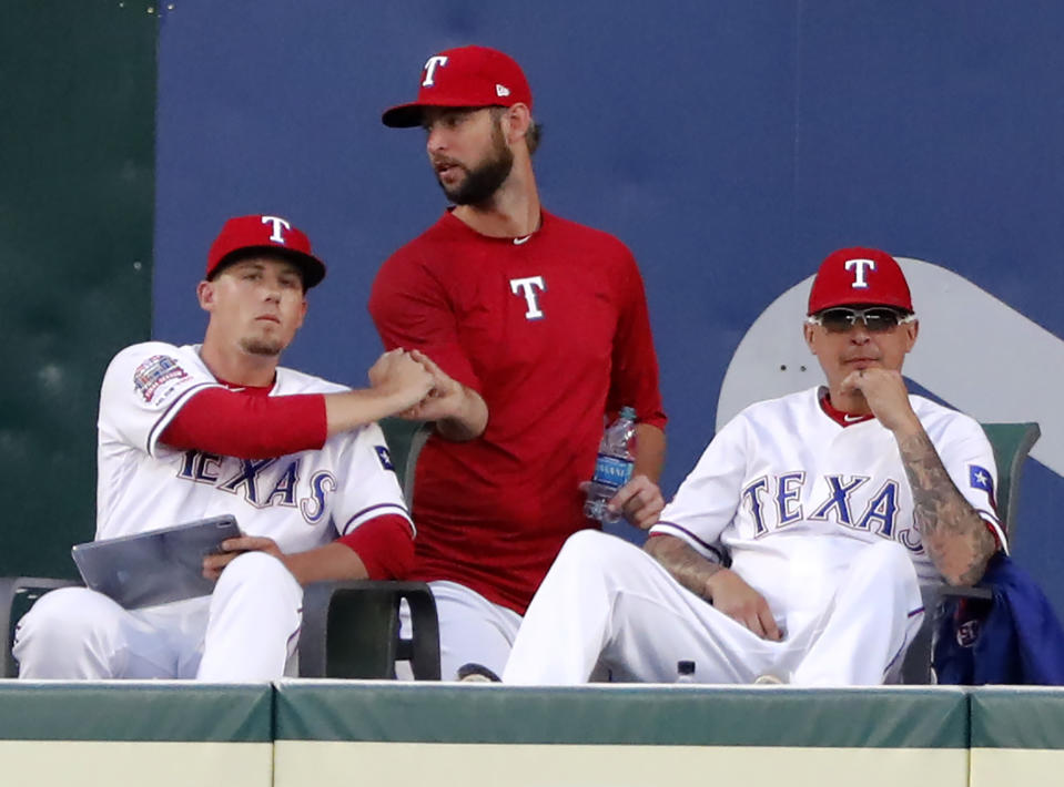 Texas Rangers' Kyle Bird, left, shakes hands with Chris Martin, center, as Jesse Chavez watches play in the third inning of a baseball game against the Seattle Mariners in Arlington, Texas, Tuesday, July 30, 2019. Martin was traded to the Atlanta Braves for a pitching prospect. (AP Photo/Tony Gutierrez)