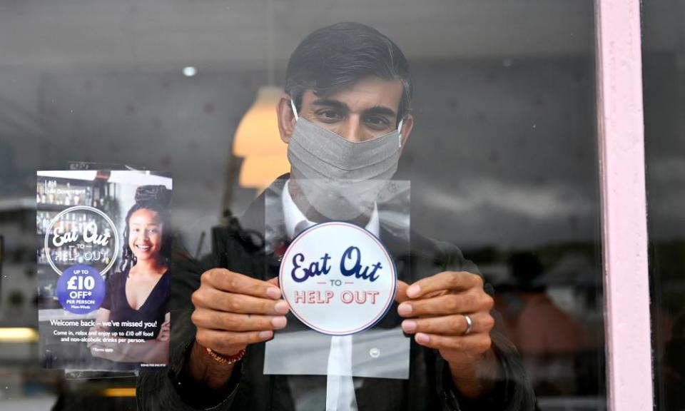 Rishi Sunak puts up a eat out to help out sticker at a restaraunt.