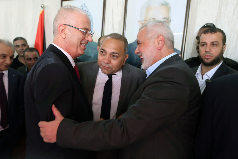 Le premier ministre palestinien Rami Hamdallah (à gauche) serre la main du chef du Hamas Ismail Haniyeh (à droite). Lors de la cérémonie organisée pour l'accueillir, Rami Hamdallah a annoncé que son gouvernement prenait la relève administrative et assumait désormais "la responsabilité de la sécurité et des points de passages comme des frontières." /Photo prise le 2 octobre 2017/REUTERS/Ibraheem Abu Mustafa