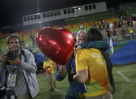 2016 Rio Olympics - Rugby - Women's Gold Medal Match Australia v New Zealand - Deodoro Stadium - Rio de Janeiro, Brazil - 08/08/2016. Rugby player Isadora Cerullo (BRA) of Brazil hugs Marjorie, a volunteer, after receiving her wedding proposal on the sidelines of the women's rugby medal ceremony. REUTERS/Alessandro Bianchi