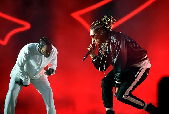 Two performers on stage, one in white attire and the other in black, engaging with the audience