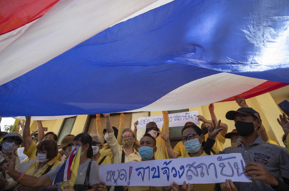 Supporter of Thailand's monarchy lift a giant national flag during a gathering stating their concern over the country's pro-democracy movement which they feel besmirches the royal institution in Bangkok, Thailand, Thursday, July 30, 2020. The demonstration was held at Democracy Monument, a traditional venue for protests of all political stripes that in recent weeks has hosted several larger pro-democracy, anti-government protests organized by students. (AP Photo/Sakchai Lalit)