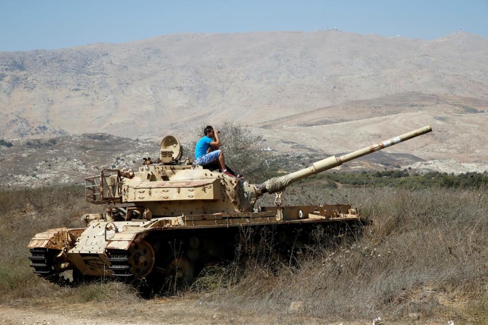 A man sits on an old tank as he watches fighting taking place in Syria as seen from the Israeli side of the border fence between Syria and the Israeli-occupied Golan Heights on September 11, 2: REUTERS
