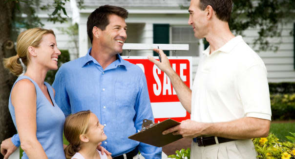 Family with estate agent outside property for sale