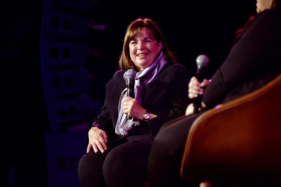 Ina Garten sitting in a chair onstage holding a microphone and doing an interview 