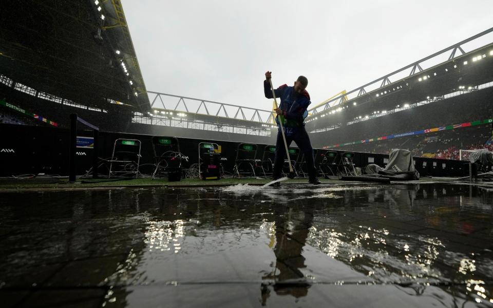 A steward clears away water inside the Dortmund stadium