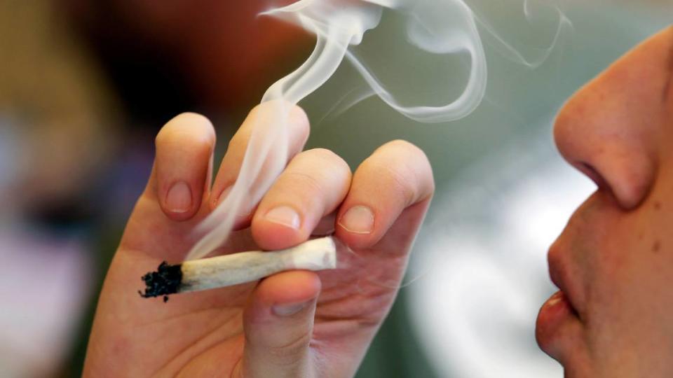 FILE - In this April 20, 2016, file photo, a man smokes a marijuana joint at a party celebrating weed in Seattle. Legalizing recreational marijuana for U.S. adults may have led to a slight decline in teen use. That’s according to research published Monday, July 8, 2019, in JAMA Pediatrics. (AP Photo/Elaine Thompson, File)