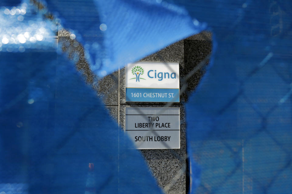 The Cigna logo is seen behind a construction fence, Friday, March 9, 2018, in Philadelphia. The insurer Cigna will acquire the nation's biggest pharmacy benefit manager, Express Scripts, the latest in a string of proposed tie-ups as health care's bill payers attempt to get a grip on rising costs. Cigna CEO David Cordani said Thursday, March 8, that the combined company will make health care more simple for customers. (AP Photo/Matt Slocum)