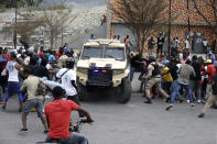 Armed off-duty police officers commandeer an armored vehicle to go shoot at army soldiers during a protest over police pay and working conditions, in Port-au-Prince, Haiti, Sunday, Feb. 23, 2020. Off-duty police officers and their supporters exchanged fire for nearly two hours with members of the newly reconstituted Haitian army in front of the national palace. (AP Photo/Dieu Nalio Chery)