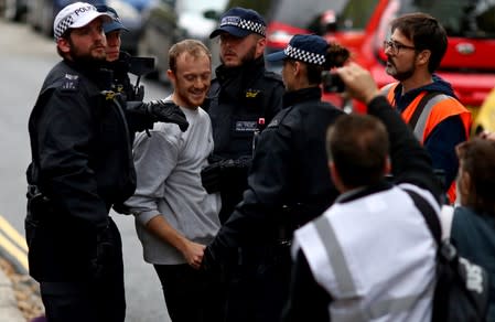 Police officers detain a man outside Lambeth County Court, during a raid on an Extinction Rebellion storage facility, in London