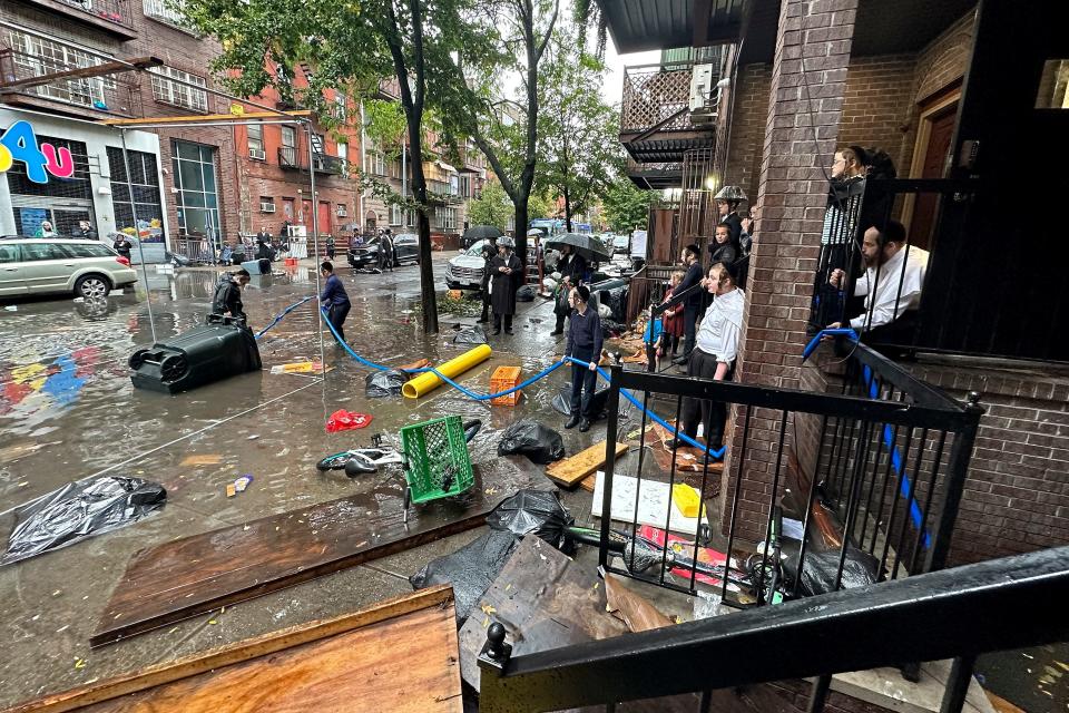 Residents watch as workers attempt to clear a drain in flood waters, Friday, Sept. 29, 2023, in the Brooklyn borough of New York. A potent rush-hour rainstorm has swamped the New York metropolitan area.