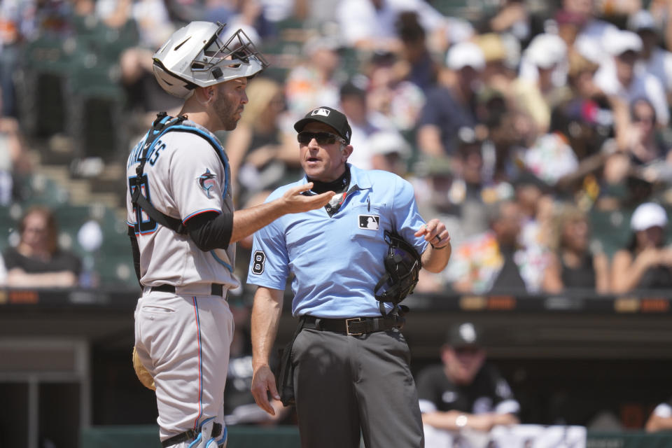 Miami Marlins catcher Jacob Stallings talks to home plate umpire Chris Guccione after Guccione called starting pitcher Sandy Alcantara for a pitch clock violation during the fourth inning of a baseball game against the Chicago White Sox, Saturday, June 10, 2023, in Chicago. (AP Photo/Charles Rex Arbogast)