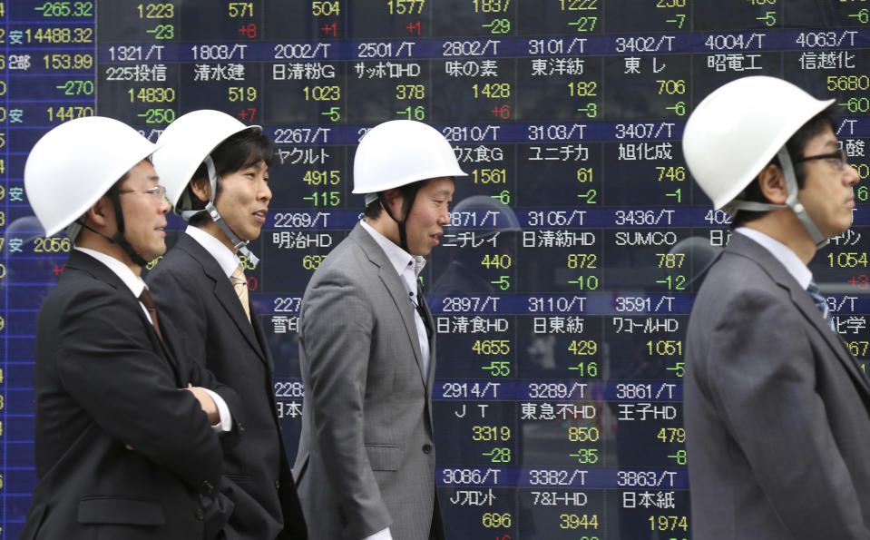 Office workers walk by an electronic stock board of a securities firm during their disaster drill in Tokyo Thursday, Feb. 13, 2014. Asian stocks were mostly lower Thursday, led by a fall in Tokyo after Wall Street ended lower for the first time this week. Japan's Nikkei 225, the region's main index, dropped 265.32 points, or 1.79 percent to 14,534.74. (AP Photo/Koji Sasahara)
