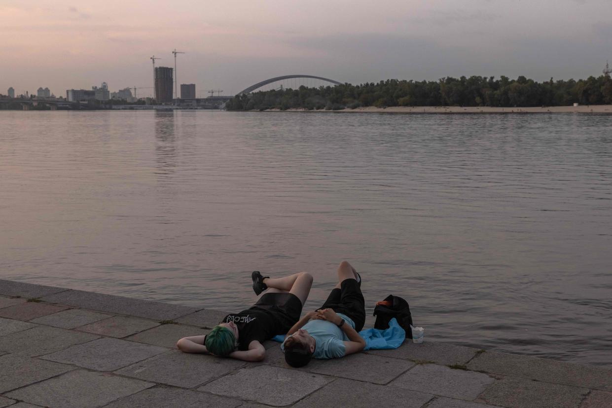 People lay at the Dnipro riverside promenade in Kyiv (AFP via Getty Images)