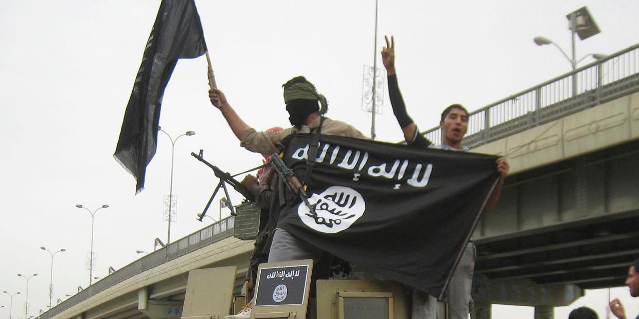 Islamic State group militants hold up their flag as they patrol in a commandeered Iraqi military vehicle in Fallujah, Iraq in 2014.